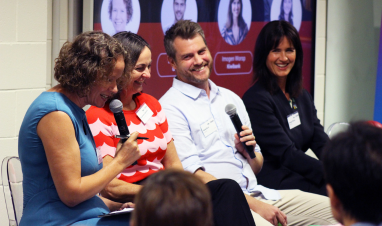 Panel smiling and presenting to the crowd. 