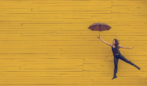 Woman Hodling an Umbrella on Yellow Background
