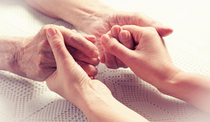 elderly person holding hands with careworker