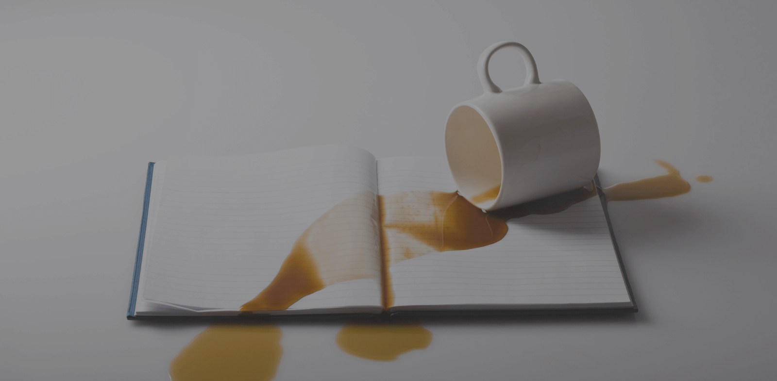 cup of coffee spilled over notebook